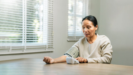 Elderly Asian woman with high blood pressure Equipped with a device to measure blood pressure...