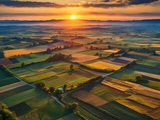 Fototapeta premium A picturesque scene unfolds as the sun sets, casting a warm glow on the patchwork of farmlands from above.