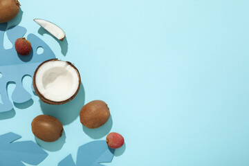 Set of tropical fruit and paper tropical leaves on blue background, space for text