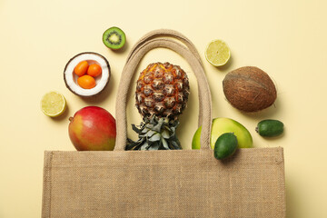 Set of tropical fruit in bag on beige background, top view