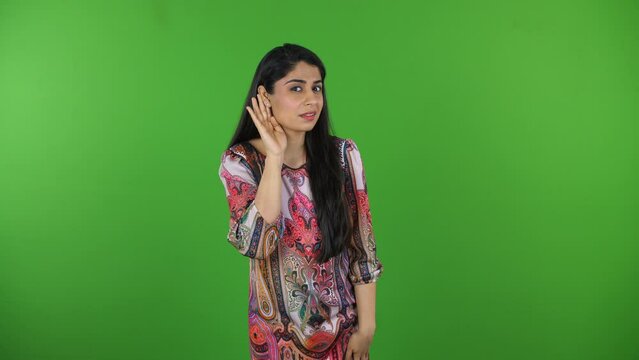 Pretty Indian girl trying to hear something on the green screen - hearing loss  isolated  deaf  human senses. Portrait shot of lady asking to repeat the information due to her hearing impairment - ...