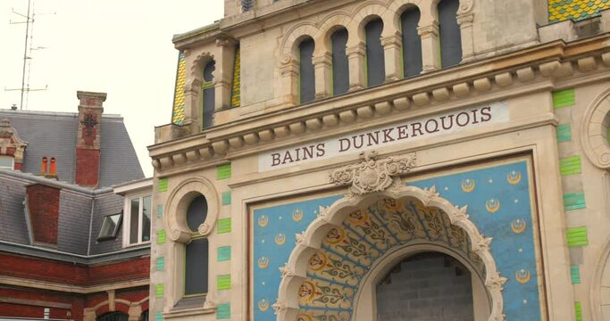 Historic Bains Dunkerquois in Dunkerque, France showcasing intricate blue and gold facade under overcast sky