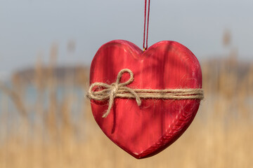 Wooden heart wrapped in rope on nature background
