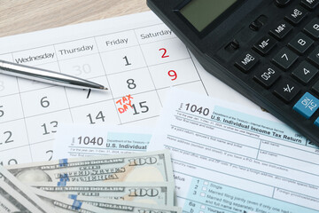Tax day. Calendar with date reminder, documents, dollar banknotes, pen and calculator on table