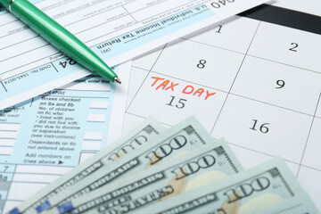 Tax day. Calendar with date reminder, documents, pen and dollar banknotes on table