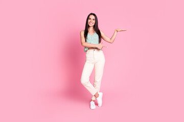 Full length photo of nice lovely cute woman wear trendy clothes presenting empty space isolated on pink color background