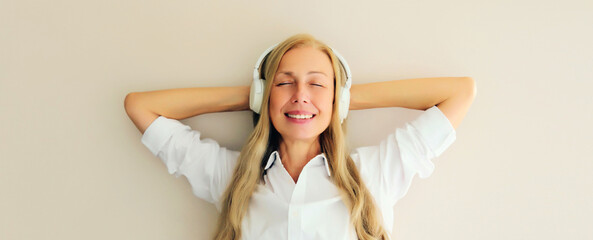 Portrait of happy relaxed middle aged woman listening to music with headphones