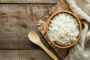 A wooden bowl filled with cooked white rice sits next to a wooden spoon on a wooden table. Generative AI
