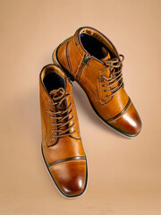 A pair of premium calfskin boots on a pink background. Vertical shot.