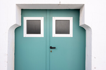 A minimalist teal door framed by white walls embodies the simple beauty of Carmona, Andalusia, Spain