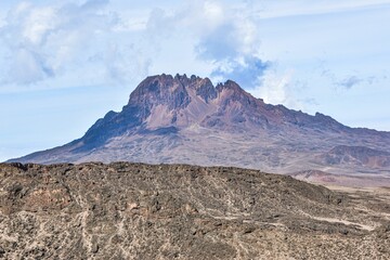 Scenic view of a vast plain with a majestic rocky Kilimanjaro mountain in the distance