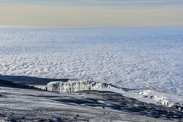 Majestic view of a snow-capped mountain peak on the background of fluffy white clouds