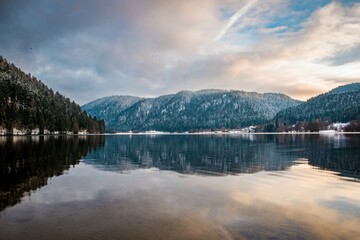 Fototapeta premium a river with snowy mountains in the background, and trees at the bank