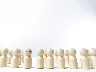 Wooden figurines with a leader and a group with partial focus. The concept of distinguishing a leader from the crowd. Sighted, intelligent, different among the blind group