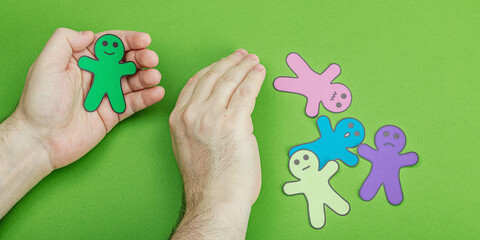 World mental health day. Male hands holding paper men figures with different emotions