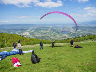 A paraglider pilot starts the takeoff while his colleagues check that the glider has inflated perfectly.