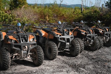 Fototapeta premium Row of four-wheeler all-terrain vehicles parked on a dirt road