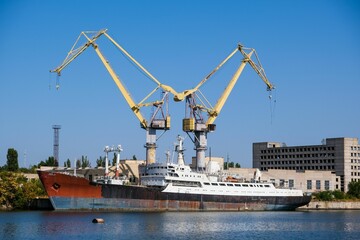 Fototapeta premium Harbor cranes and a ship under repair at the berth