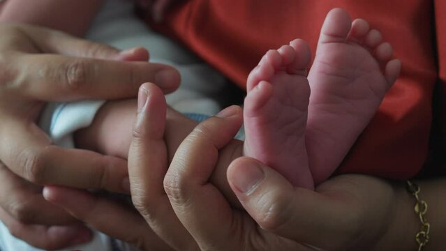 Mother's hands carefully holding the baby legs while sleeping