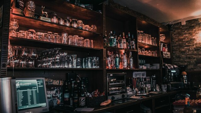 Wooden shelf filled with an assortment of alcoholic bottles and glasses at a bar in Achern