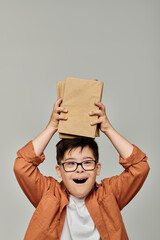 Cute boy with Down syndrome playfully holding stack of books.