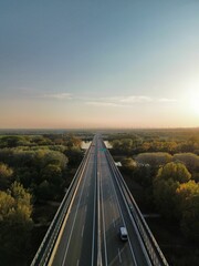 Fototapeta premium Picturesque scene of a bridge spanning a tranquil body of water surrounded by lush green forest
