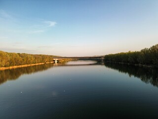 a river with a bridge over it next to trees and blue sky