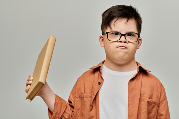 little boy with Down syndrome with glasses engrossed in a book.