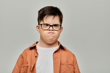 A little boy with Down syndrome with glasses showcasing his playful and mischievous side. © Bliss