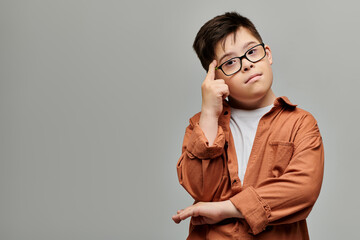 Adorable boy with Down syndrome posing thoughtfully with hand on head.