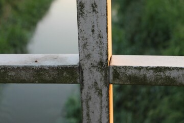 Fototapeta premium Fence overlooking tranquil river, with lush green grass in the foreground on a bright and sunny day