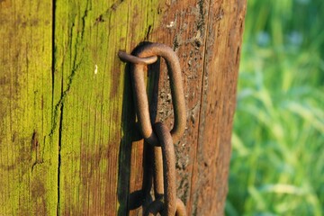 a locked old rusted lock hangs from a fence post