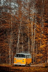 Obraz premium Orange vintage van driving through the forests of Parc du Pilat in France in autumn.