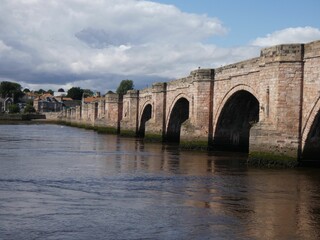 Fototapeta premium an arch shaped brick bridge across the water in the middle of town