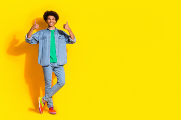 Full size portrait of nice young man thumb up empty space wear denim shirt isolated on yellow color...