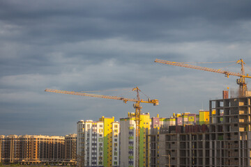 Fototapeta premium Construction site with cranes in the evening. Kyiv landmark at sunset. New buildings under construction. Residential downtown in Kyiv, Ukraine. Building industry. Urban architecture.