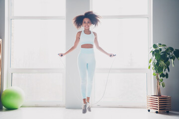 Full length photo of happy smiling lady activewear jumping rope indoors room home house