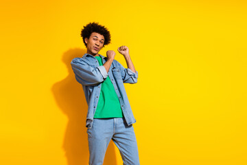 Photo of nice young man enjoy dancing wear denim shirt isolated on yellow color background