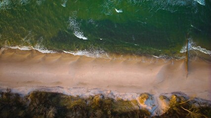 Golden hour aerial: Sandy beach, gently rolling waves..