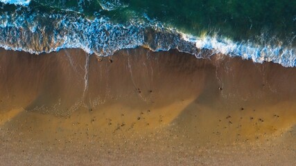 Drone shot: Empty sandy shore, golden sunlight.