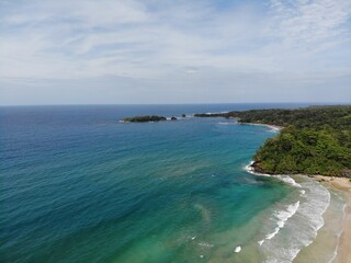 Aerial view of a turquoise sea against a lush green tropical island
