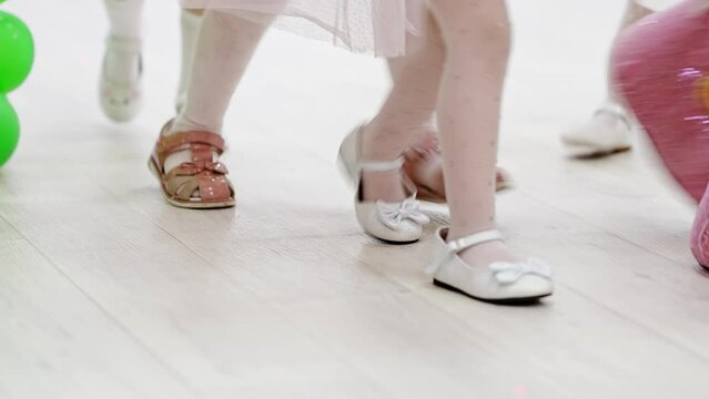 Faceless legs of little dancing girls with an animator. Holiday in kindergarten.
