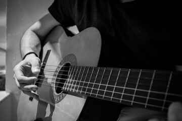 Fototapeta premium Close-up of a man with an acoustic guitar in his hands in grayscale