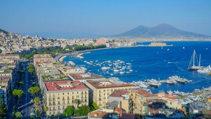 Fototapeta premium Aerial view of vibrant coastal cityscape with blue ocean and white sailboats in the foreground