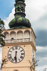 Clock mounted on a white building adorned with green domes