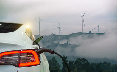 Electric car charging with wind turbines in the background, highlighting renewable energy and...