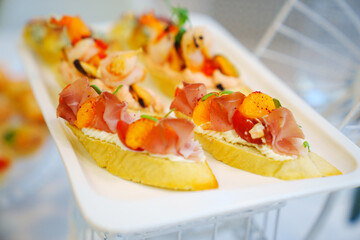 Baguette with cottage cheese, cured meat and fruit. A delicious delicacy appetizer for a banquet. Catering.