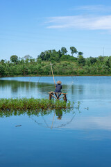 Tranquil fishing scene on a serene lake in Lombok, Indonesia, with a fisherman casting his net...