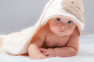 beautiful newborn laid and looking from under blanket 