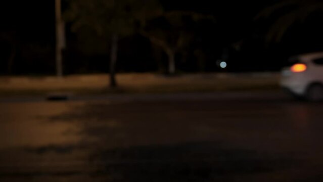 Urban night car traffic in focus, side view. Cars pass in front of the camera at night, a frame without focus. High quality 4k footage